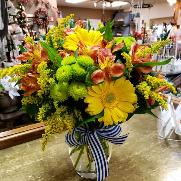 Bouquet of yellow gerbera daisies and orange alstroemeria in a glass vase
