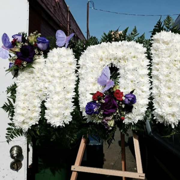 Three white floral standing sprays with purple and red accents