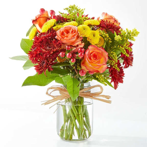 Bouquet of orange roses and red chrysanthemums in a glass vase