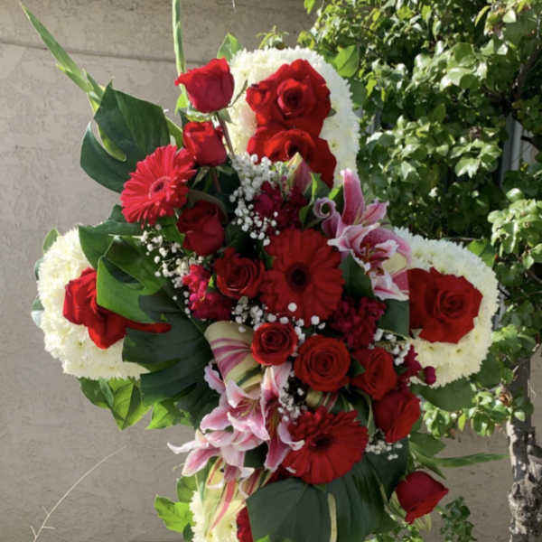 Standing floral cross with red roses and white flowers on an easel