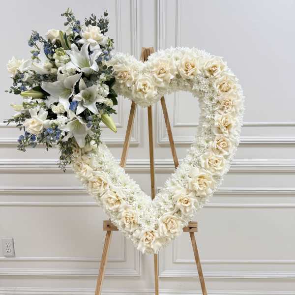 Heart-shaped floral wreath on an easel with white roses and lilies