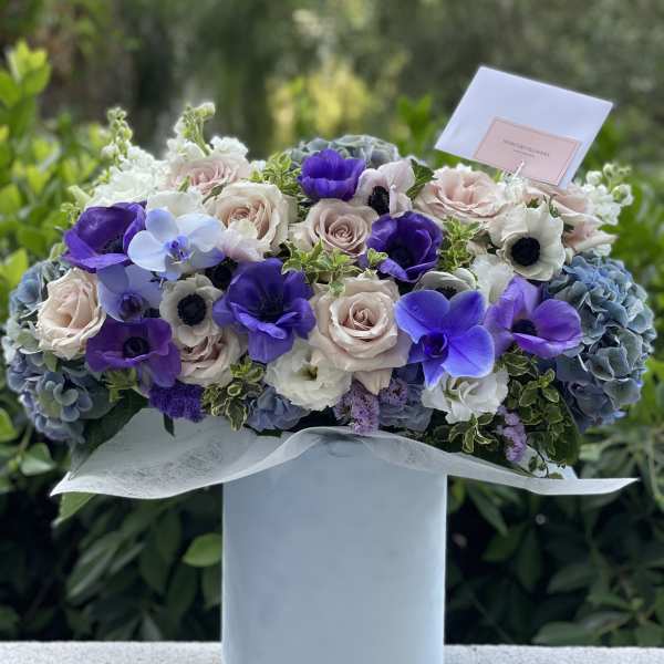 Lavender, white, and pink bouquet in a pale blue box