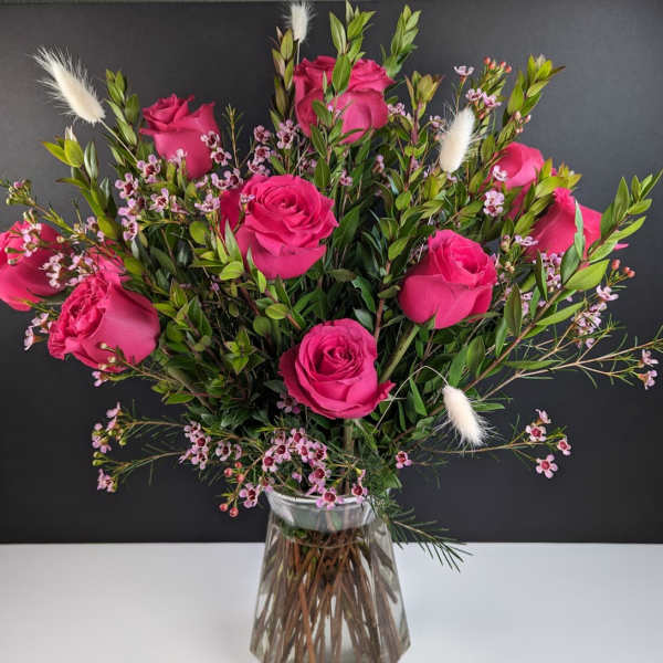Pink roses arranged in a clear glass vase with small filler flowers