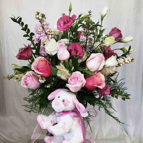 Pink and white flower arrangement with a plush bunny in a glass vase
