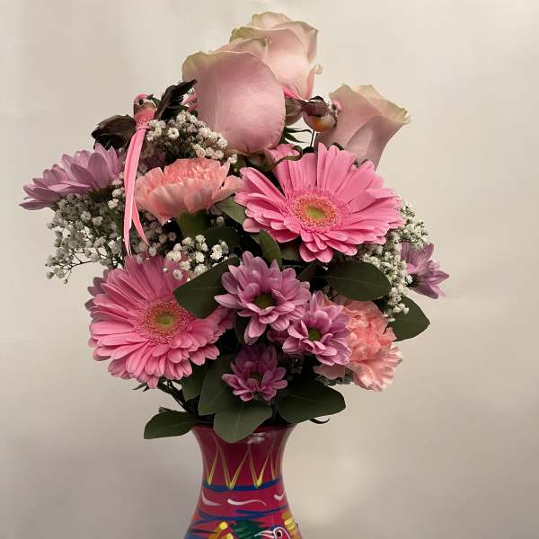 Pink and lavender flower arrangement in a colorful painted vase
