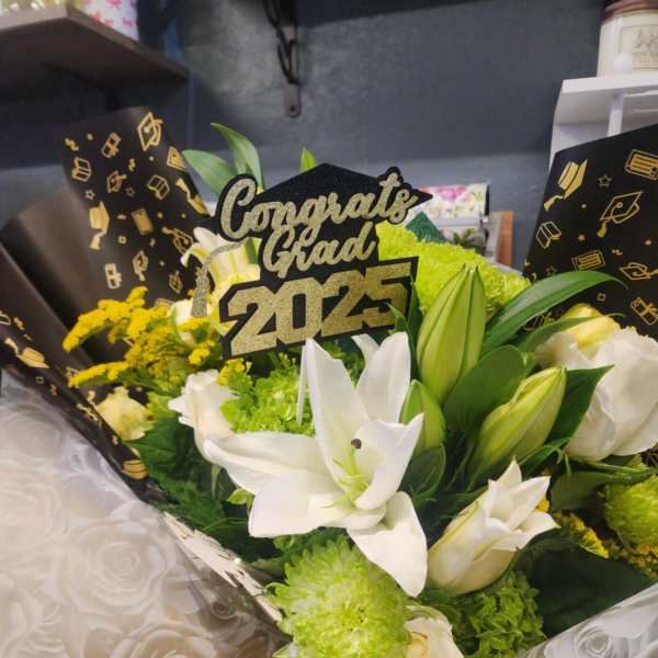 Graduation bouquet of white lilies and green mums with a Congrats Grad 2025 topper