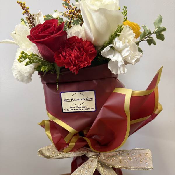 Bouquet of red and white roses with carnations wrapped in burgundy paper