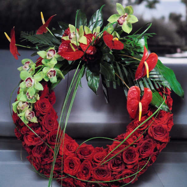 Circular wreath of red roses with green orchids and red tropical flowers on one side
