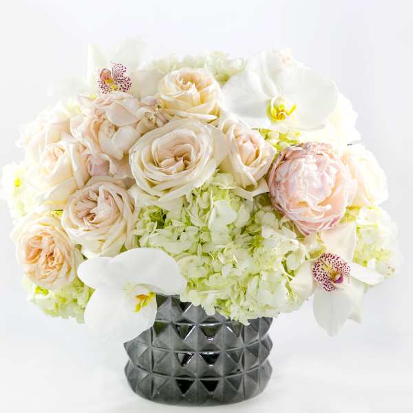 Cream and white floral arrangement in a dark textured vase