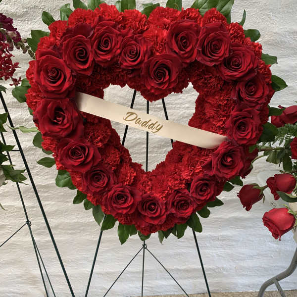 Heart-shaped red rose and carnation wreath with a ribbon reading Daddy
