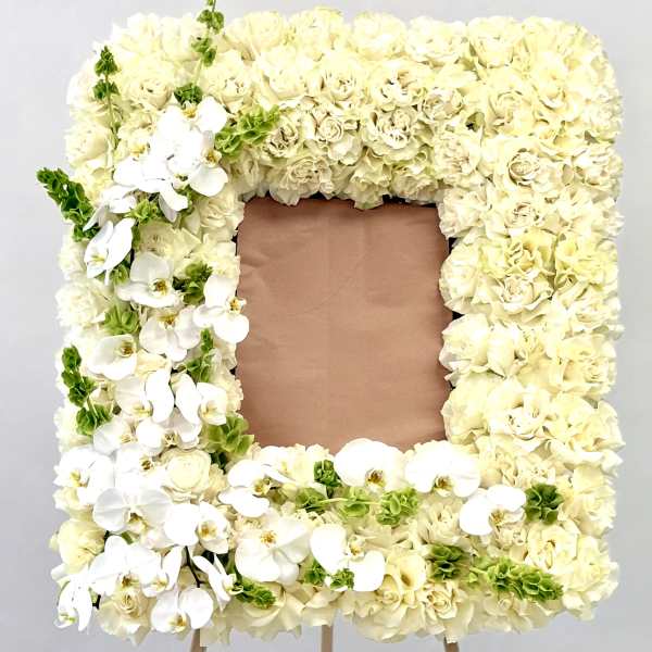 Square floral frame of cream roses and white orchids on an easel