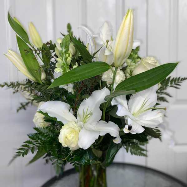 White lilies and roses arranged in a glass vase