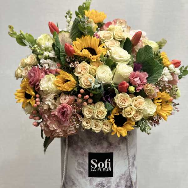 Mixed bouquet of roses, sunflowers, and tulips in a marbled hatbox