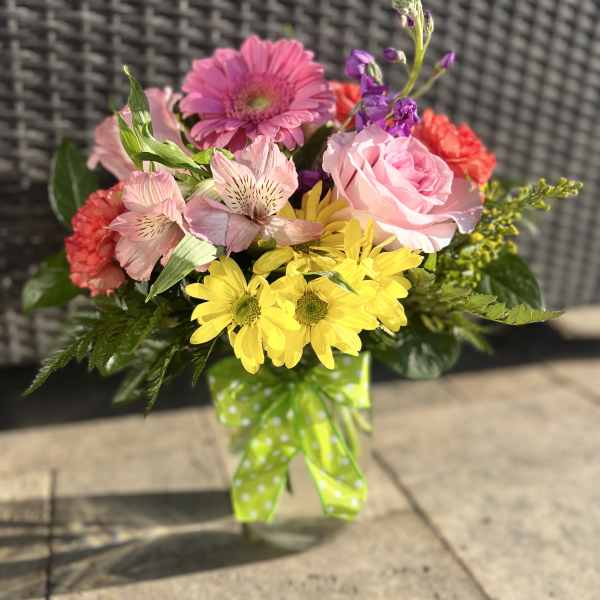 Mixed bouquet of pink, yellow, and red flowers tied with a green polka-dot ribbon