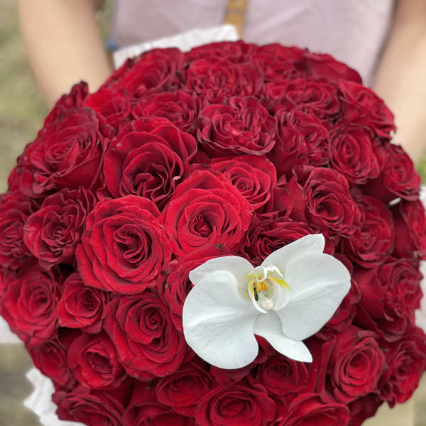 Round bouquet of red roses with a white orchid accent