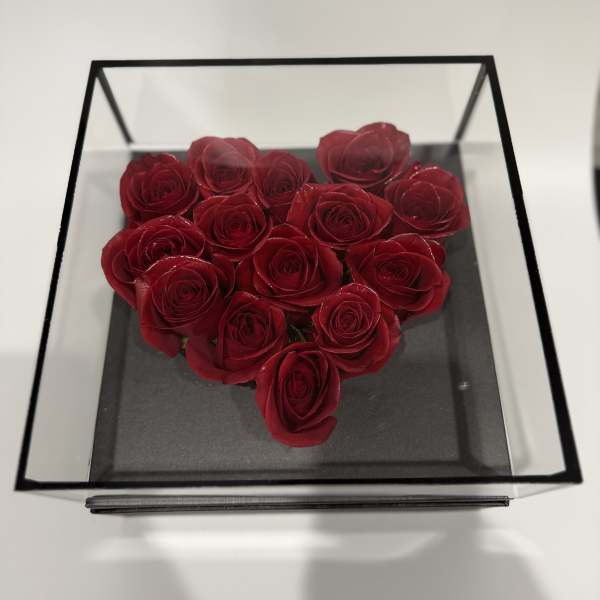 Heart-shaped arrangement of red roses in a clear square box