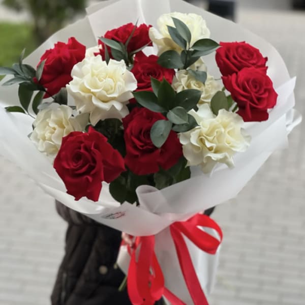 Bouquet of red and white roses wrapped in white paper with a red ribbon