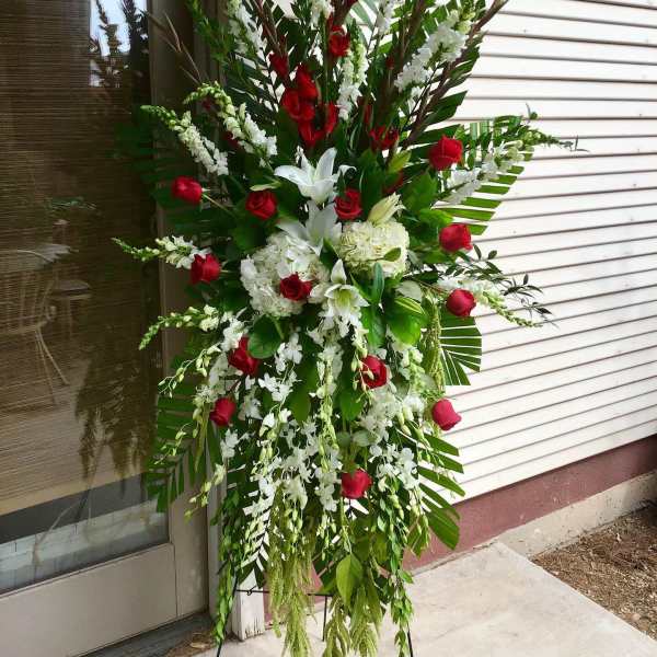 Standing floral spray with red roses and white lilies on a metal easel