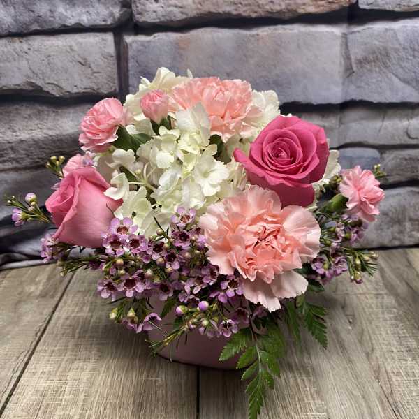 Pink and white floral arrangement in a low container