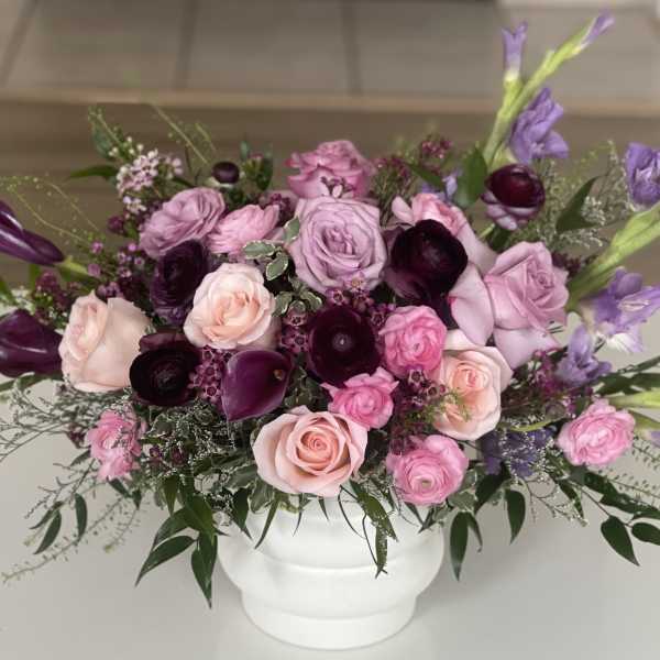 Pink and purple rose arrangement in a white vase
