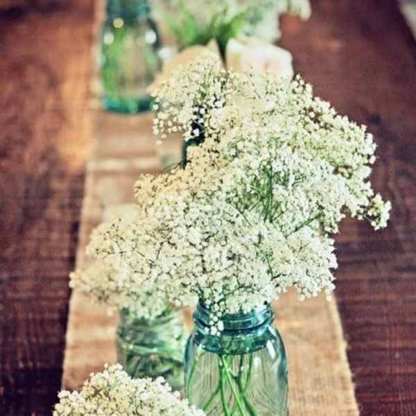 White baby's breath in small blue glass jars on a table runner