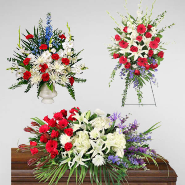 Three floral funeral sprays with red, white, and purple flowers around a casket