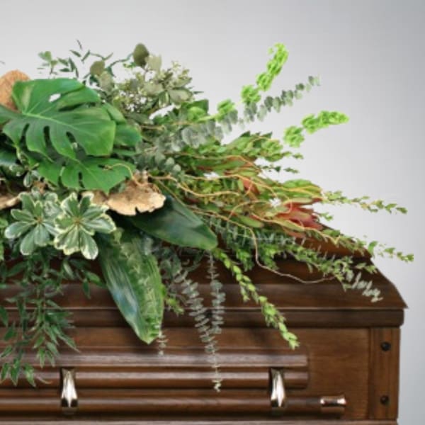 Green floral arrangement on a wooden casket