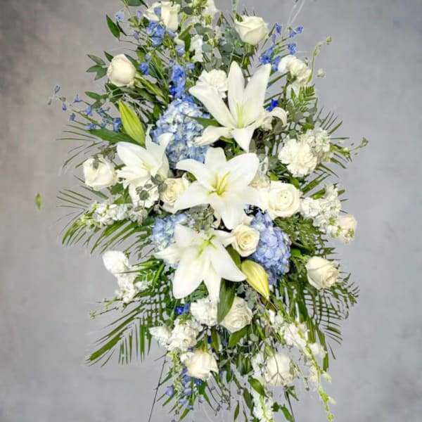 Tall white floral spray with lilies, roses, and blue accents