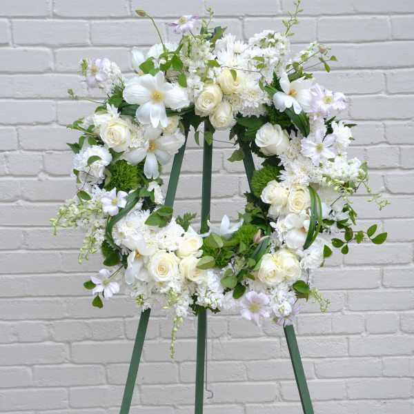 White floral wreath on a green easel stand