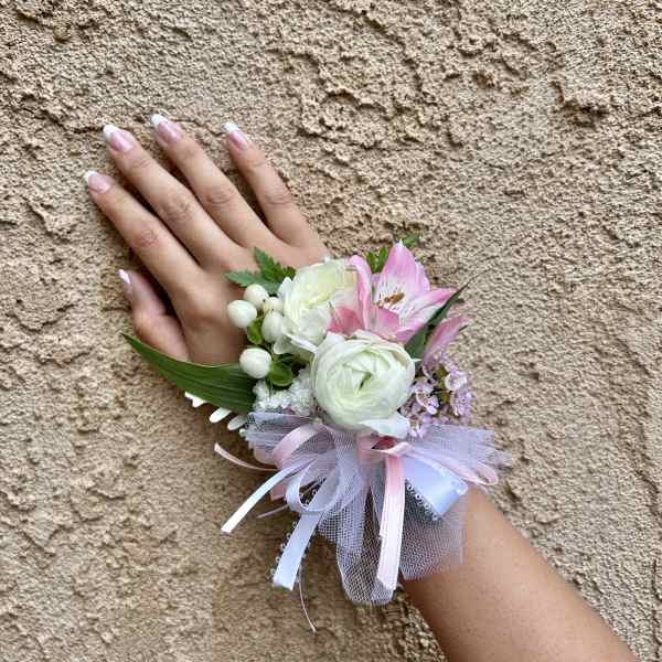Pink and white wrist corsage with ribbon on a hand