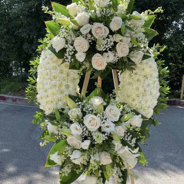 Large white floral standing spray on an easel with roses and lilies