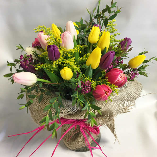 Bouquet of multicolored tulips in a burlap-wrapped vase