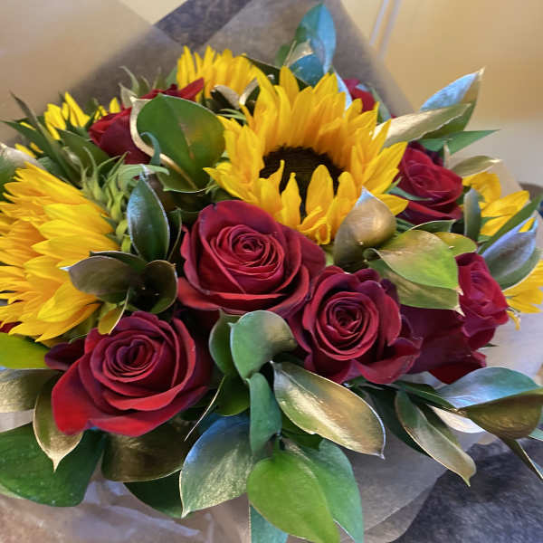 Bouquet of red roses and yellow sunflowers wrapped in paper