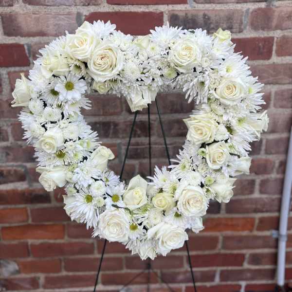 Heart-shaped white floral wreath on a stand