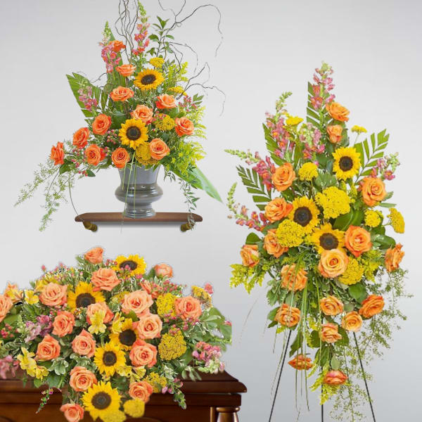 Set of orange rose and yellow sunflower sympathy arrangements with casket spray, easel spray, and urn piece.