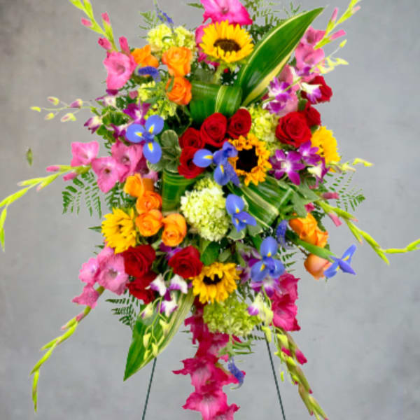 Tall colorful standing floral spray with roses, sunflowers, and orchids