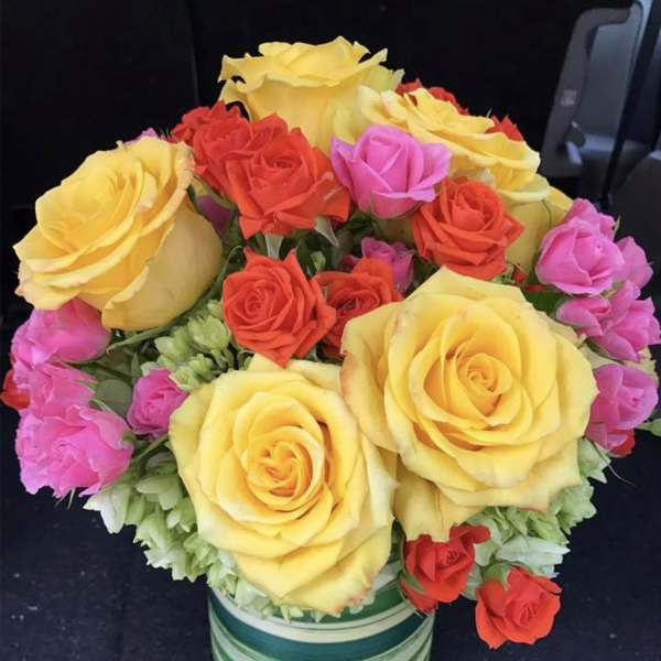 Bouquet of yellow, red, and pink roses in a striped vase