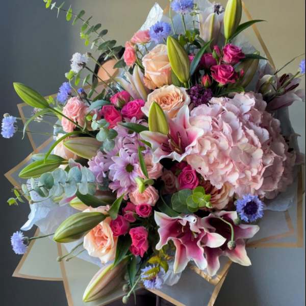 Large bouquet of pink lilies, roses, hydrangea, and blue accent flowers