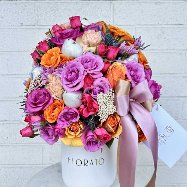 Mixed bouquet of pink, purple, and orange roses in a white hat box with ribbon