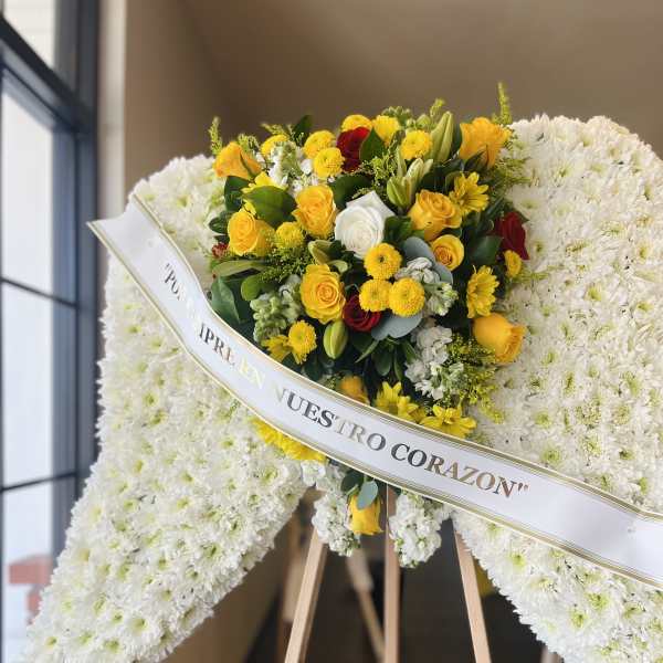 White funeral wreath with yellow and red roses on a wooden easel