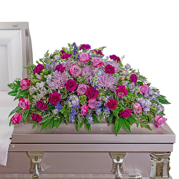 Large pink and purple floral casket spray on a light-colored casket