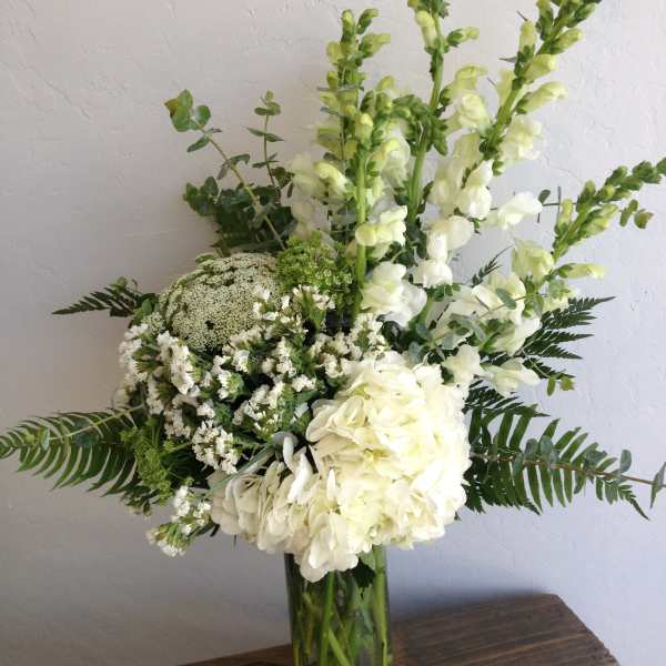 White flowers and greenery arranged in a clear glass vase