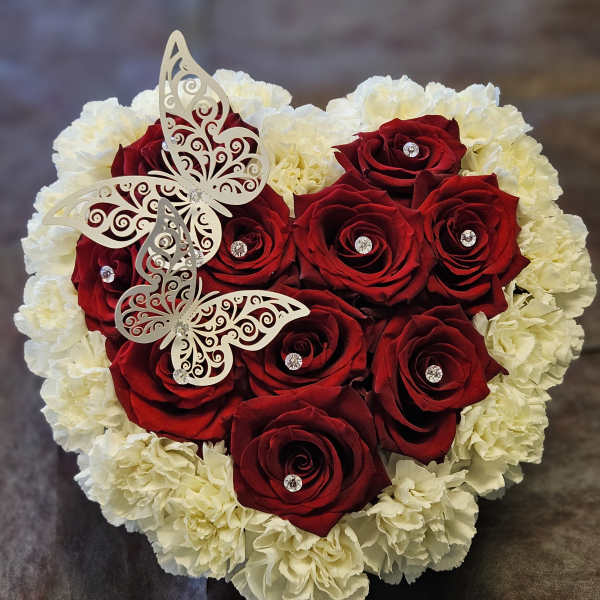 Heart-shaped bouquet of red roses and white carnations with butterfly decorations