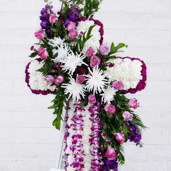 Large floral cross arrangement with pink roses, white chrysanthemums, and purple orchids