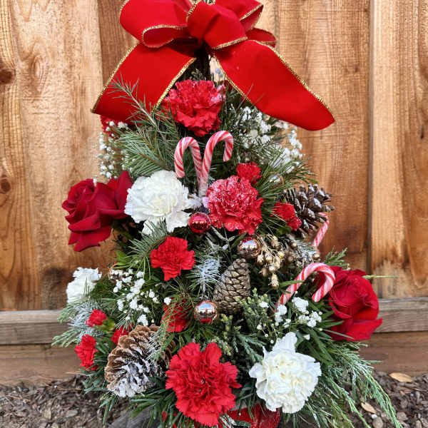Christmas tree arrangement with red and white flowers, candy canes, and a large red bow