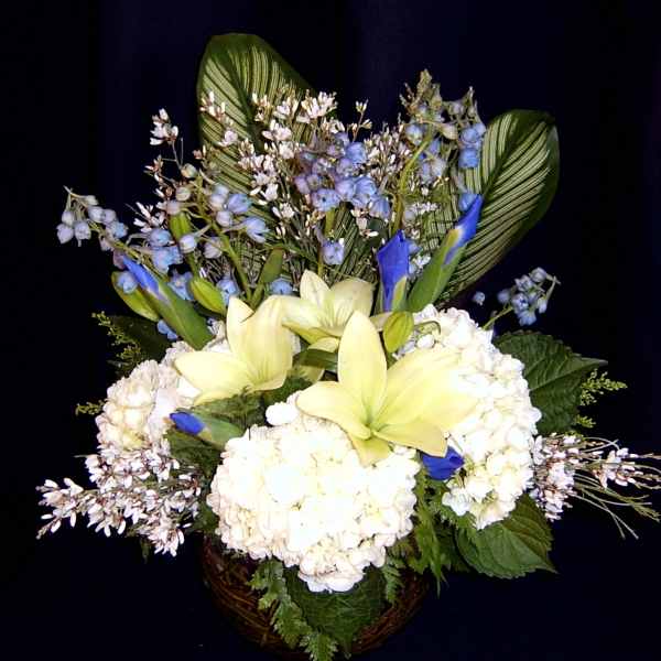 White hydrangeas and pale yellow lilies in a basket with blue accents