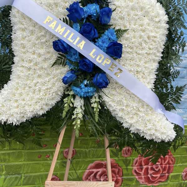 Large funeral wreath with white flowers and blue roses on an easel