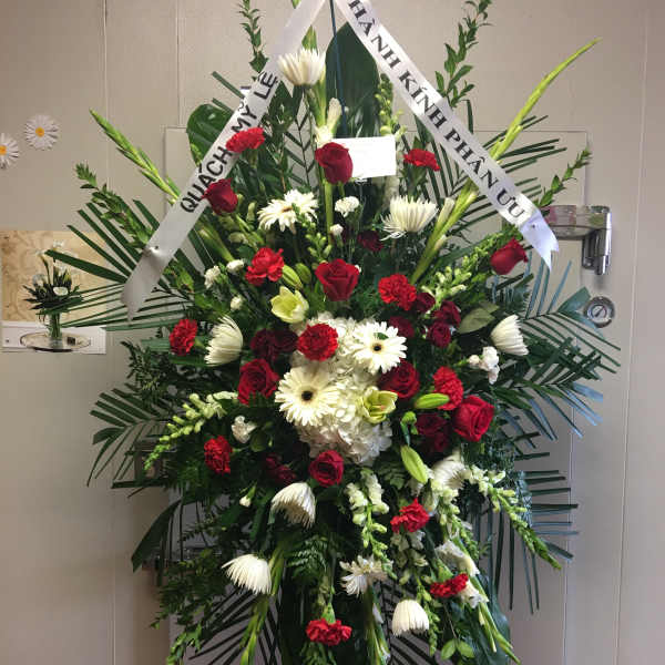Standing funeral spray with red and white flowers on an easel