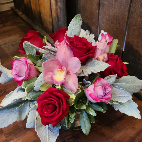 Bouquet of red and pink roses with a pink orchid in a low vase