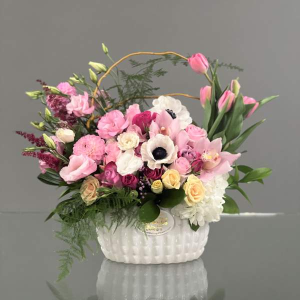Pink and white mixed flower arrangement in a white basket vase